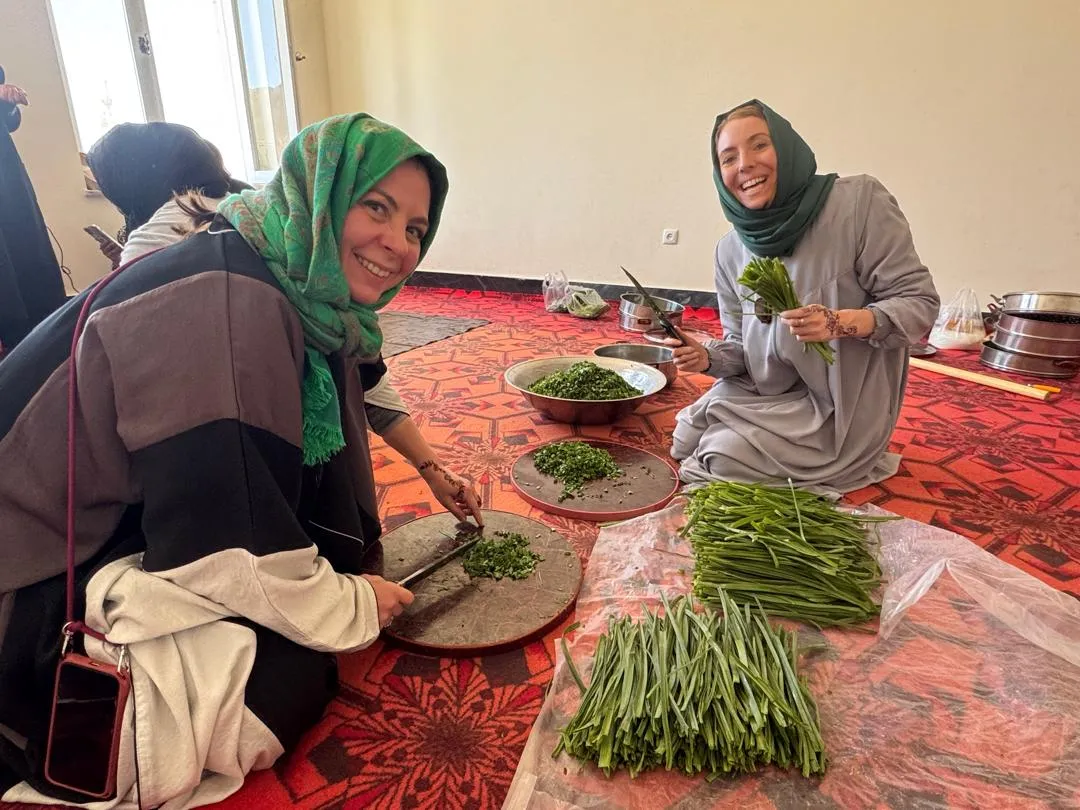 Female Travelers from Italy and the UK chopping leeks for Ashak during our cooking class in Bamiyan.